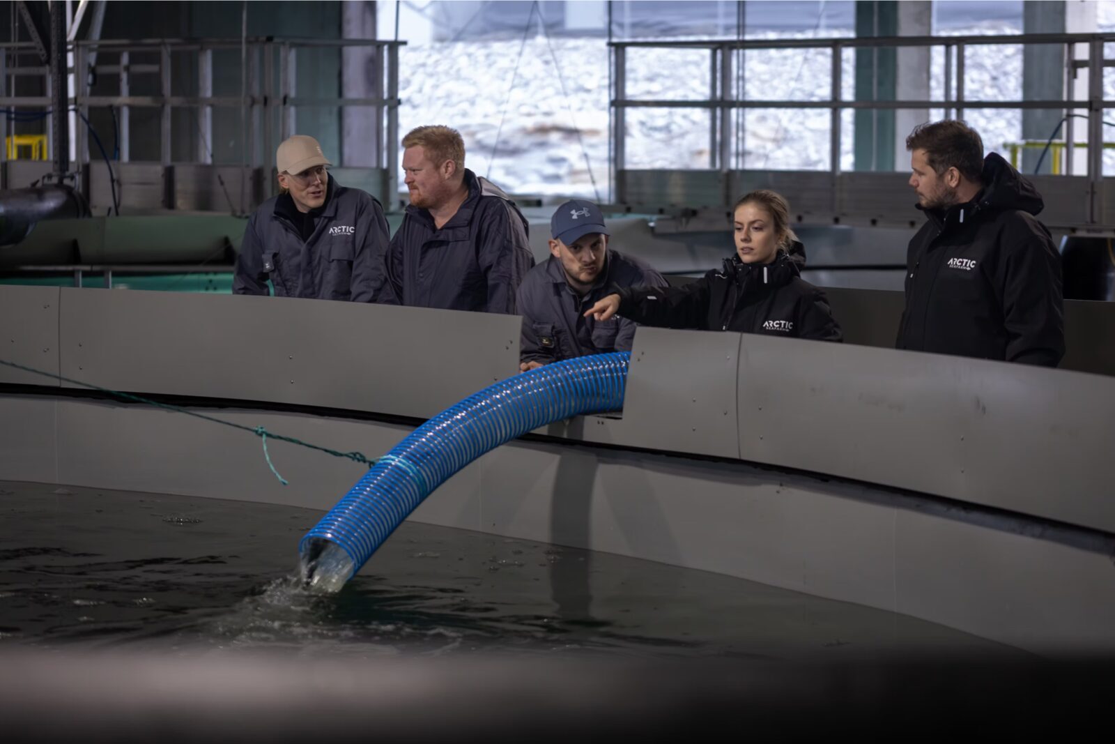 Arctic Seafarm-ansatte ser på vanninntaket til et oppdrettskar på Nesna